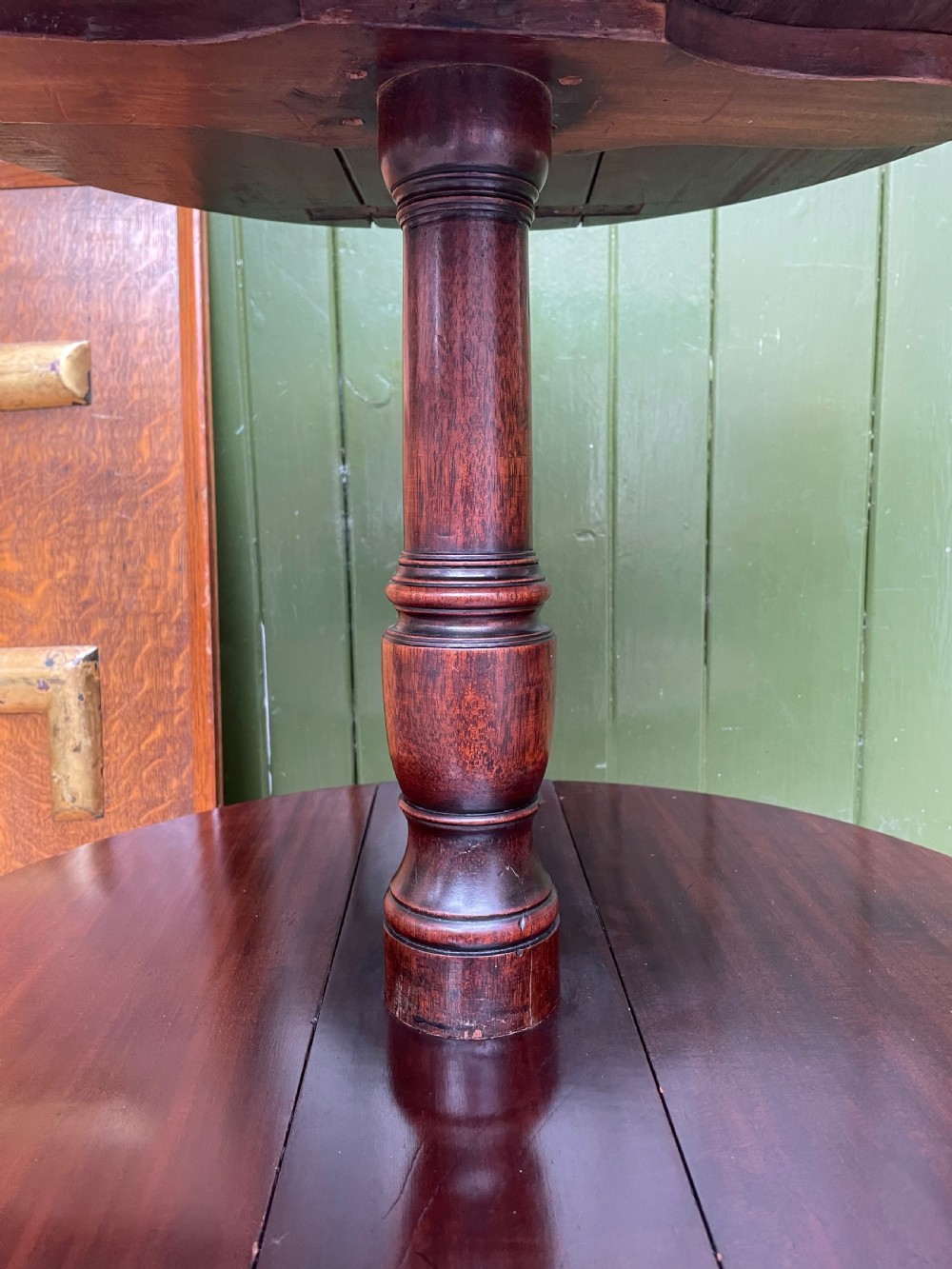 A late eighteenth-century George III mahogany two-tiered dumb waiter featuring drop-leaf circular shelves and a turned column on a tripod base with brass castors. View III