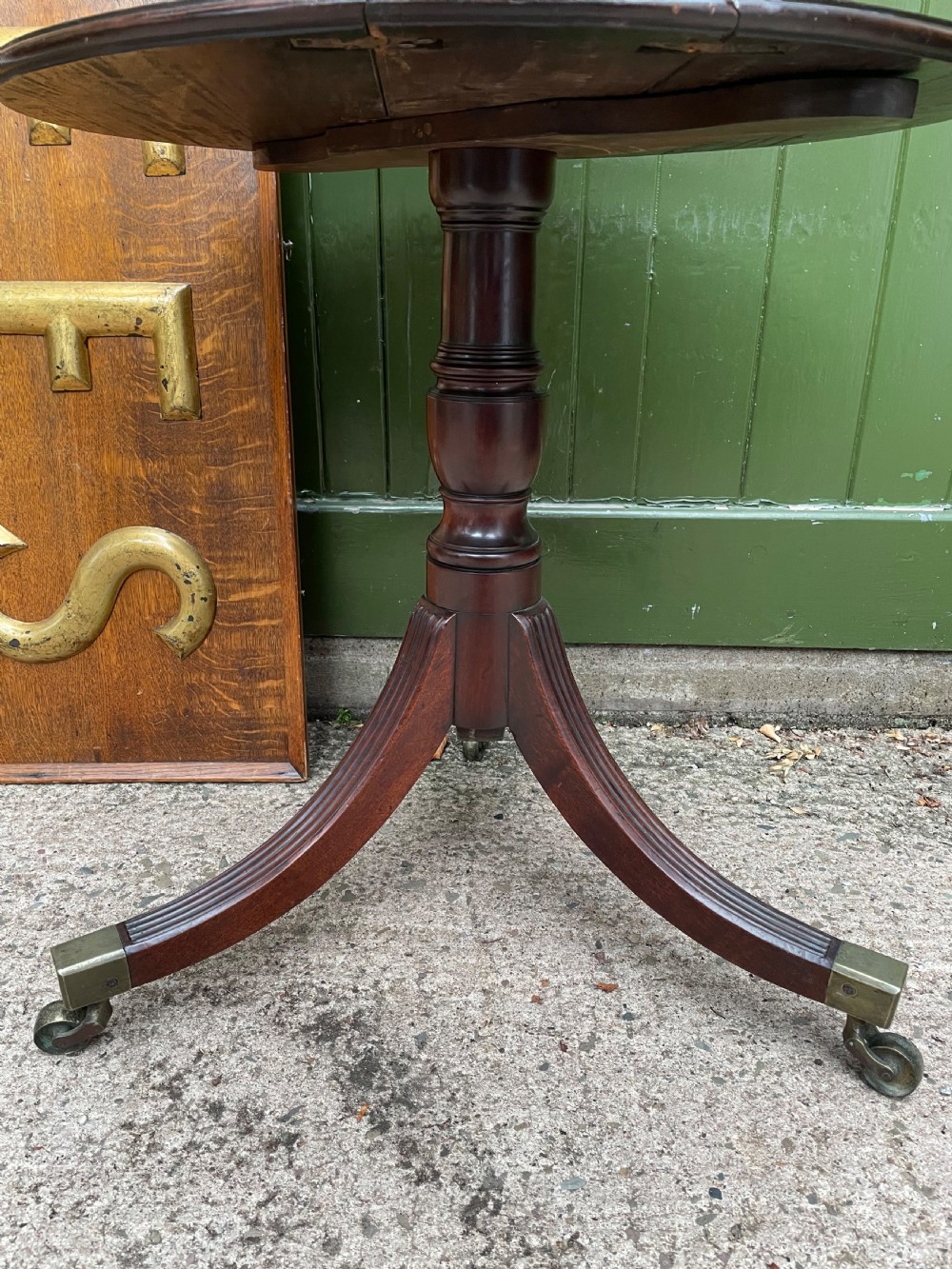 A late eighteenth-century George III mahogany two-tiered dumb waiter featuring drop-leaf circular shelves and a turned column on a tripod base with brass castors. View IV