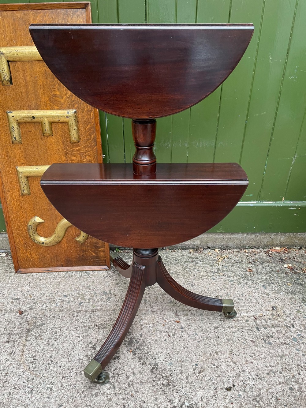 A late eighteenth-century George III mahogany two-tiered dumb waiter featuring drop-leaf circular shelves and a turned column on a tripod base with brass castors. View VI