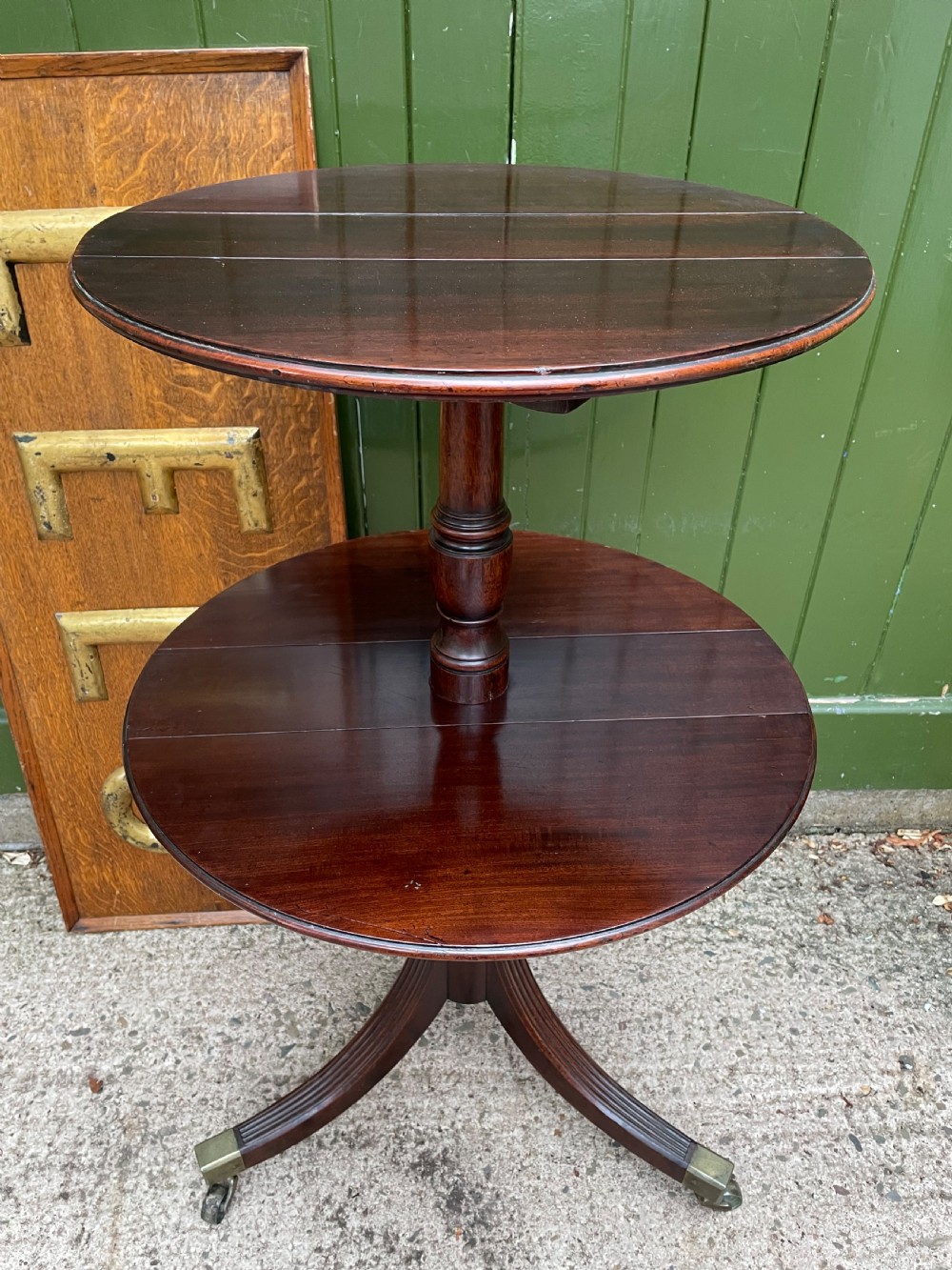 A late eighteenth-century George III mahogany two-tiered dumb waiter featuring drop-leaf circular shelves and a turned column on a tripod base with brass castors. View IX