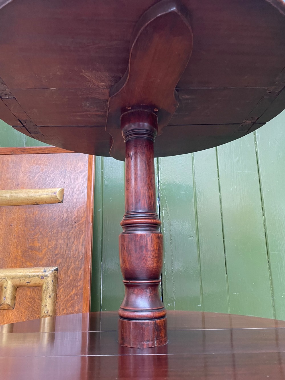 A late eighteenth-century George III mahogany two-tiered dumb waiter featuring drop-leaf circular shelves and a turned column on a tripod base with brass castors. View X