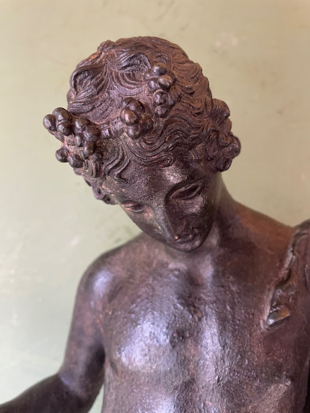 A dark patinated bronze figure depicting the nude classical youth Dionysus standing in contrapposto pose on a circular moulded base. View III