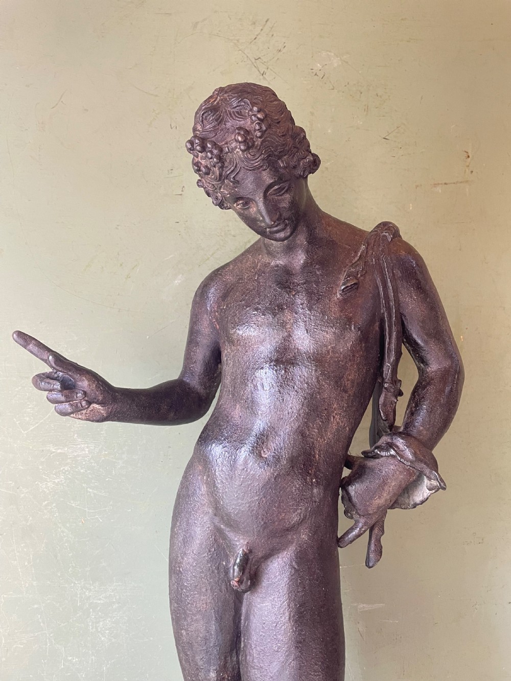 A dark patinated bronze figure depicting the nude classical youth Dionysus standing in contrapposto pose on a circular moulded base. View V