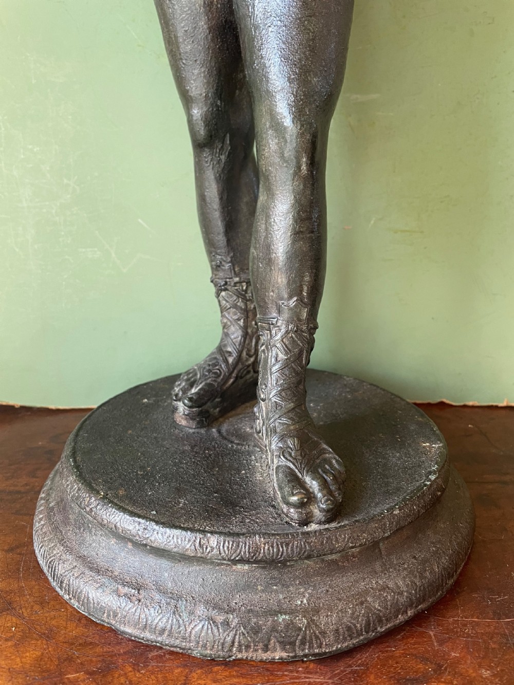 A dark patinated bronze figure depicting the nude classical youth Dionysus standing in contrapposto pose on a circular moulded base. View VI
