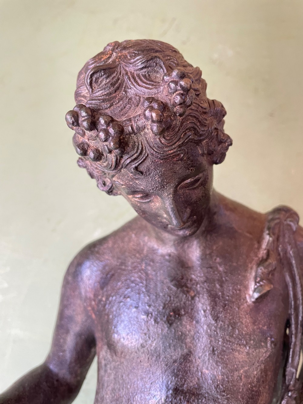 A dark patinated bronze figure depicting the nude classical youth Dionysus standing in contrapposto pose on a circular moulded base. View XV