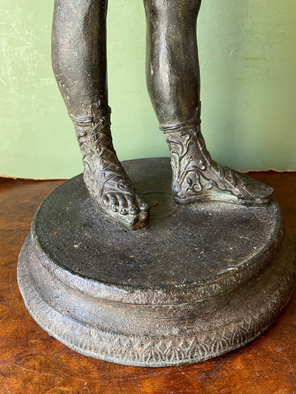 A dark patinated bronze figure depicting the nude classical youth Dionysus standing in contrapposto pose on a circular moulded base. View XVI