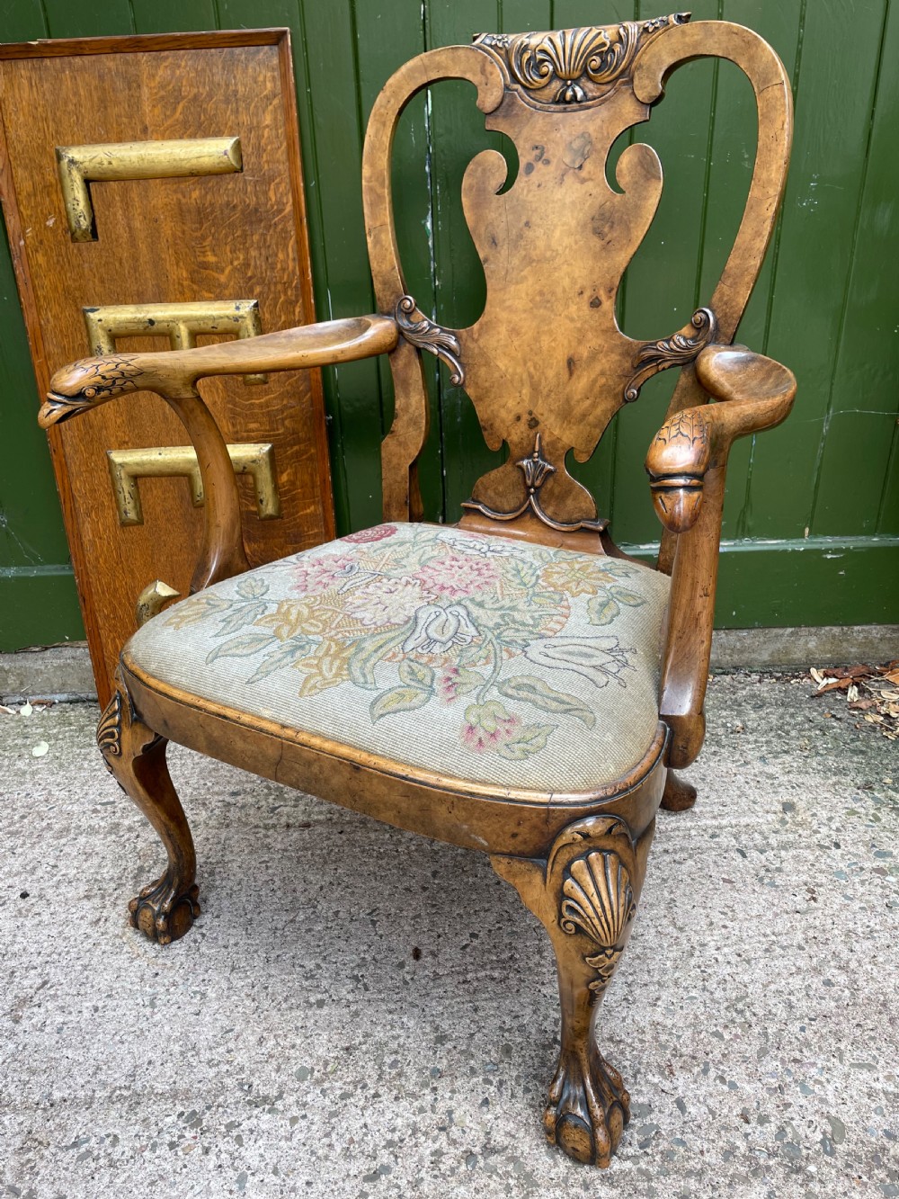 A carved walnut open armchair featuring carved eagle head arm terminals, a vasiform splat back, and floral tapestry upholstery.