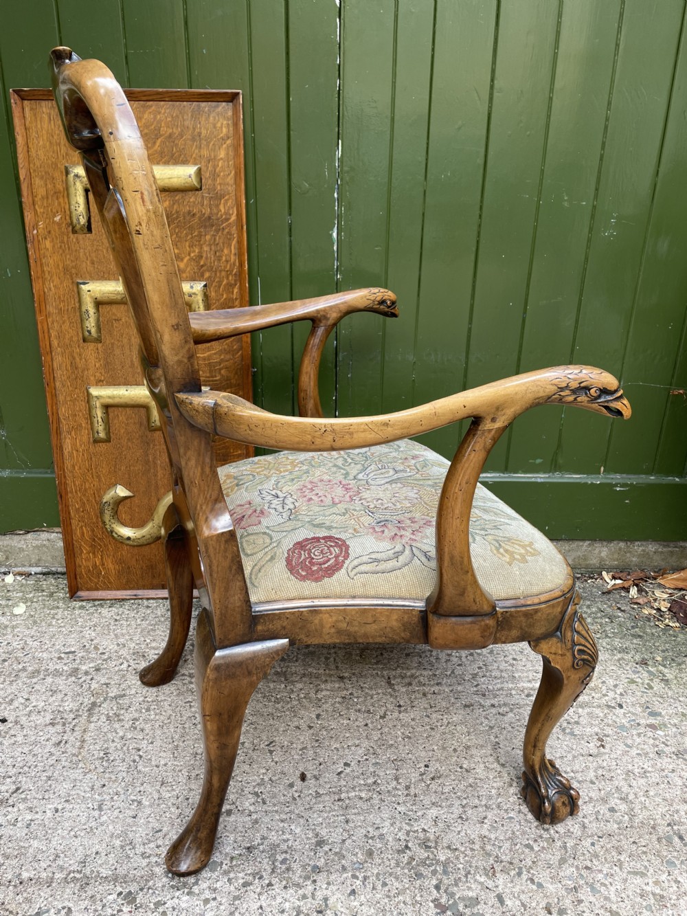 A carved walnut open armchair featuring carved eagle head arm terminals, a vasiform splat back, and floral tapestry upholstery. View XXIV