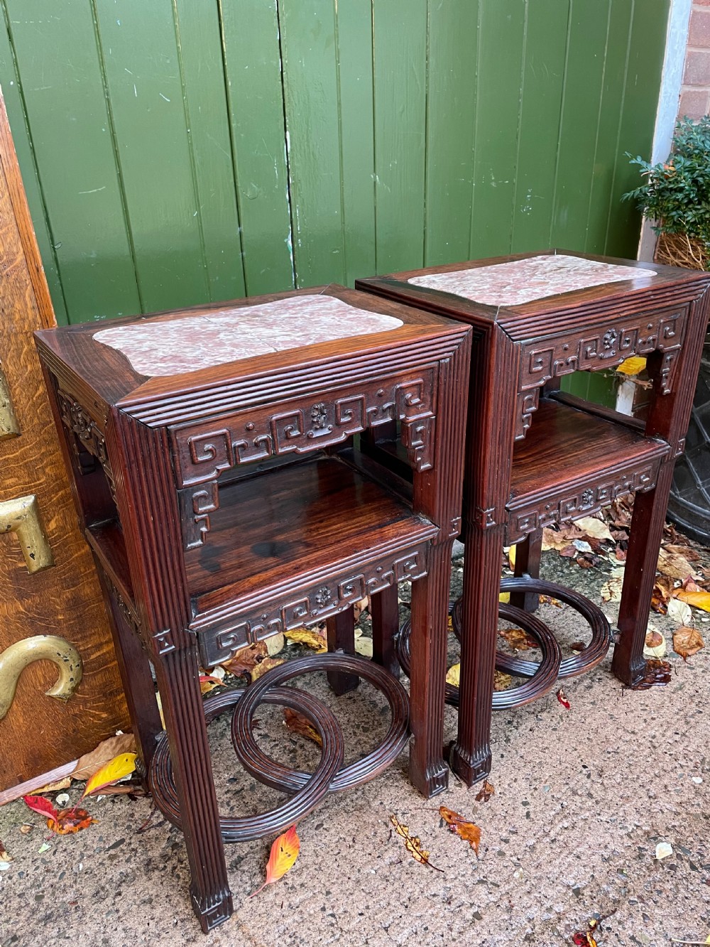 A pair of late nineteenth-century Chinese carved dark hardwood two-tier stands featuring inset marble tops, carved openwork aprons, and interlocking ring stretchers. View II