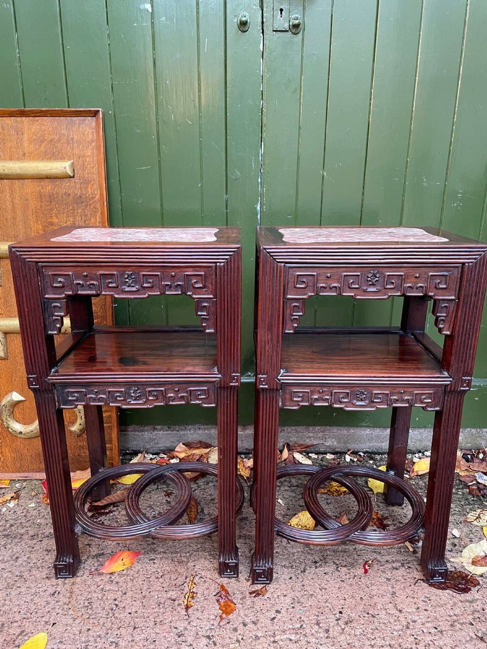 A pair of late nineteenth-century Chinese carved dark hardwood two-tier stands featuring inset marble tops, carved openwork aprons, and interlocking ring stretchers. View V