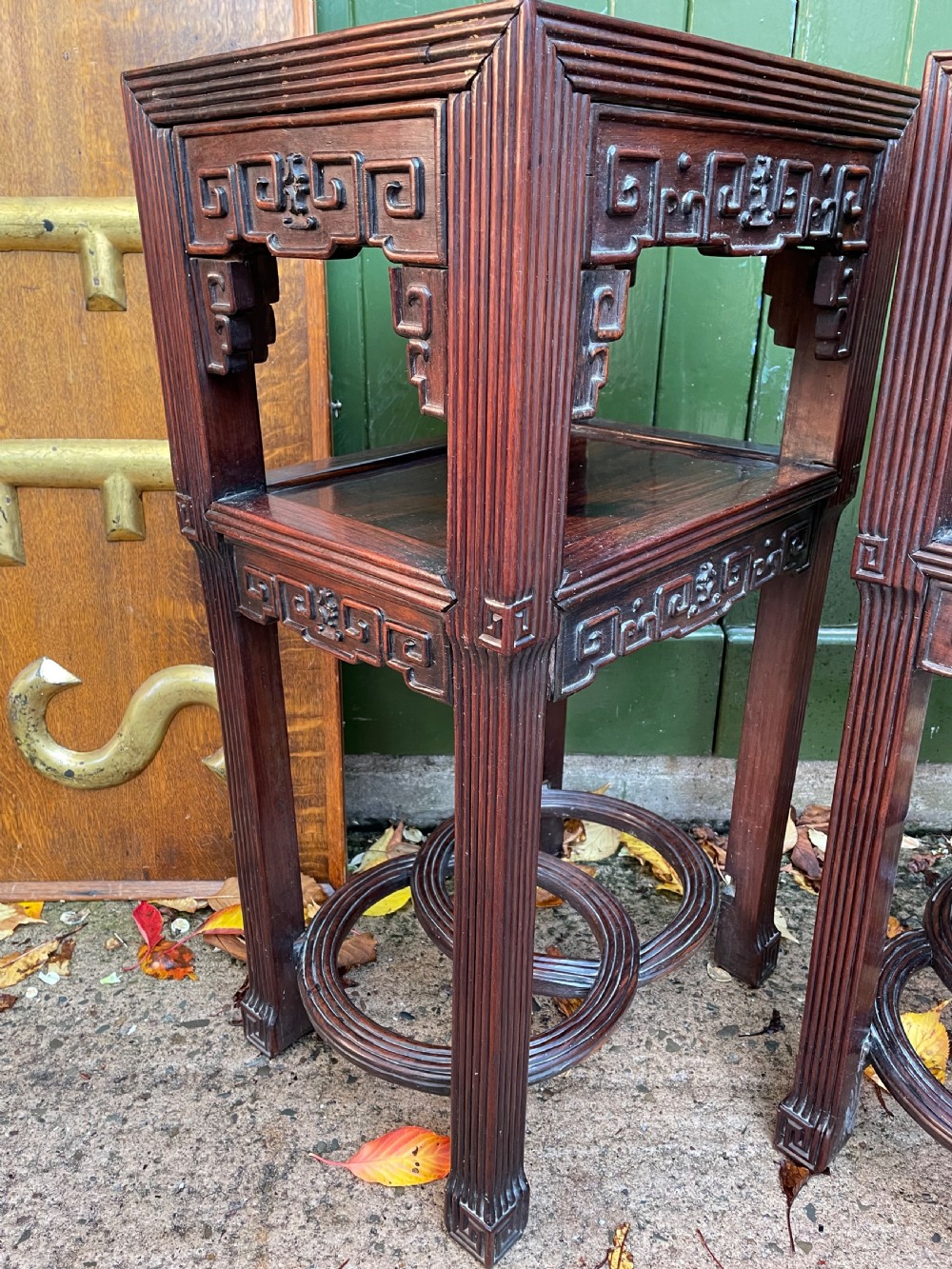 A pair of late nineteenth-century Chinese carved dark hardwood two-tier stands featuring inset marble tops, carved openwork aprons, and interlocking ring stretchers. View X