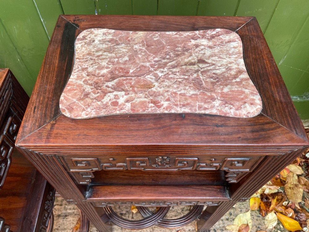 A pair of late nineteenth-century Chinese carved dark hardwood two-tier stands featuring inset marble tops, carved openwork aprons, and interlocking ring stretchers. View XIII