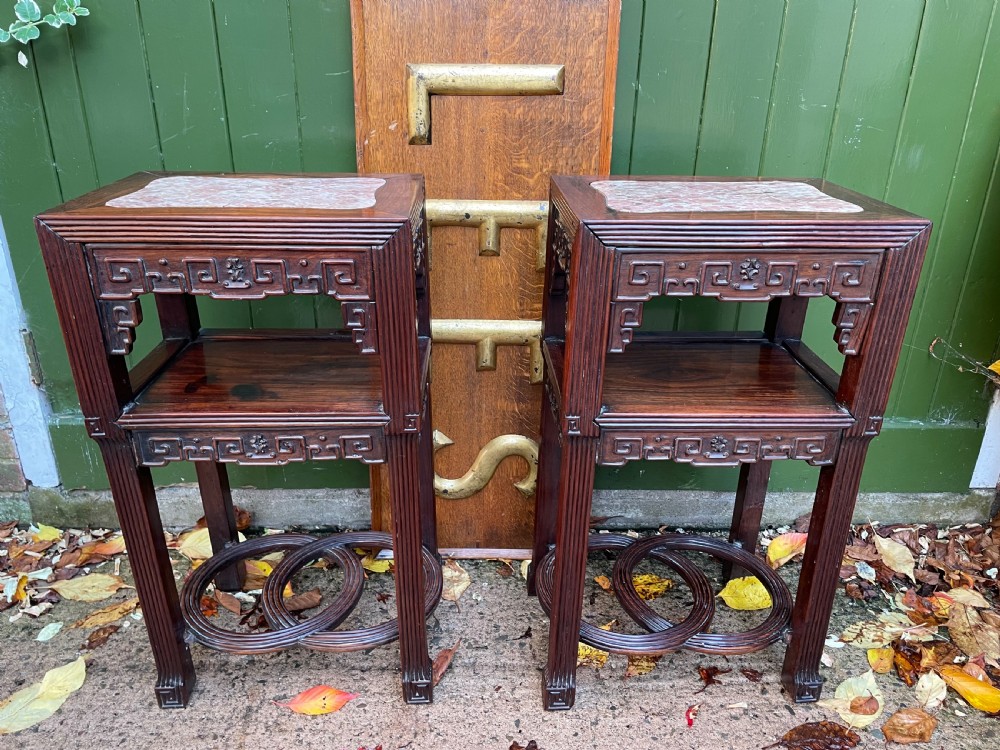 A pair of late nineteenth-century Chinese carved dark hardwood two-tier stands featuring inset marble tops, carved openwork aprons, and interlocking ring stretchers. View XVII