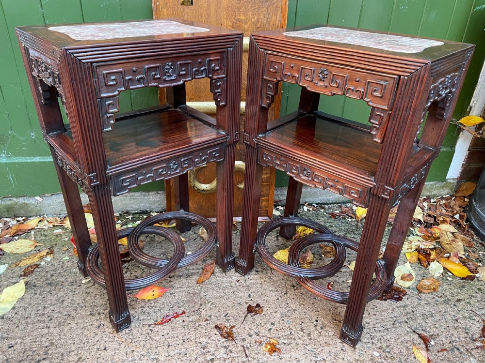 A pair of late nineteenth-century Chinese carved dark hardwood two-tier stands featuring inset marble tops, carved openwork aprons, and interlocking ring stretchers. View XXII