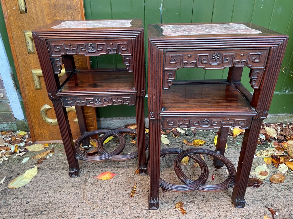 A pair of late nineteenth-century Chinese carved dark hardwood two-tier stands featuring inset marble tops, carved openwork aprons, and interlocking ring stretchers. View XXIV
