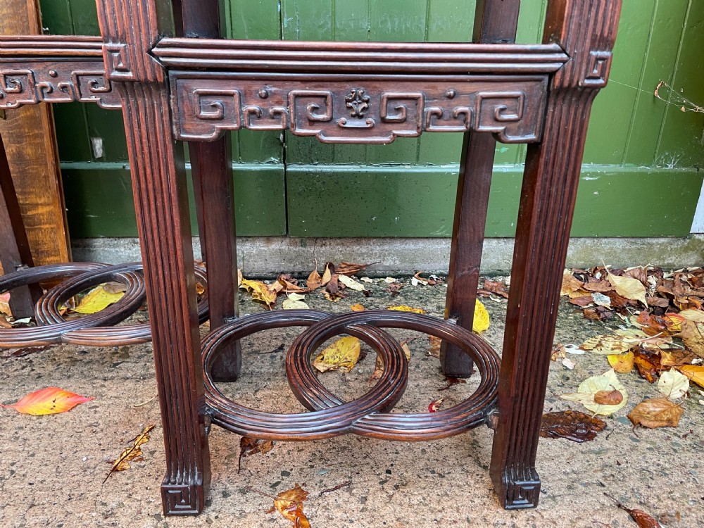 A pair of late nineteenth-century Chinese carved dark hardwood two-tier stands featuring inset marble tops, carved openwork aprons, and interlocking ring stretchers. View XXV