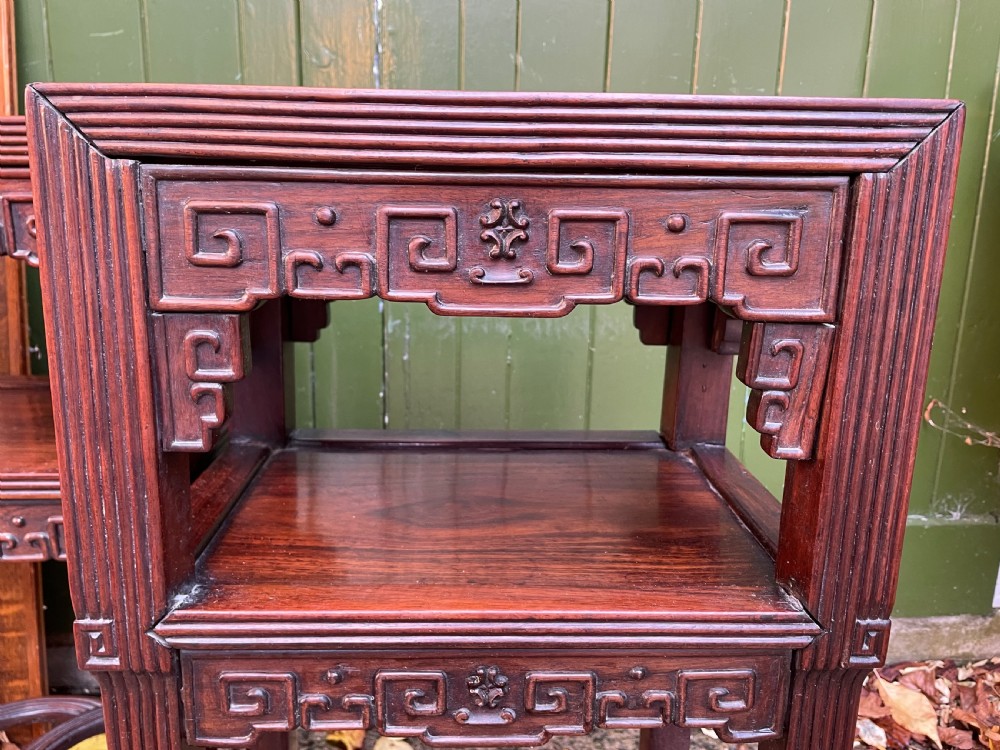A pair of late nineteenth-century Chinese carved dark hardwood two-tier stands featuring inset marble tops, carved openwork aprons, and interlocking ring stretchers. View XXVI