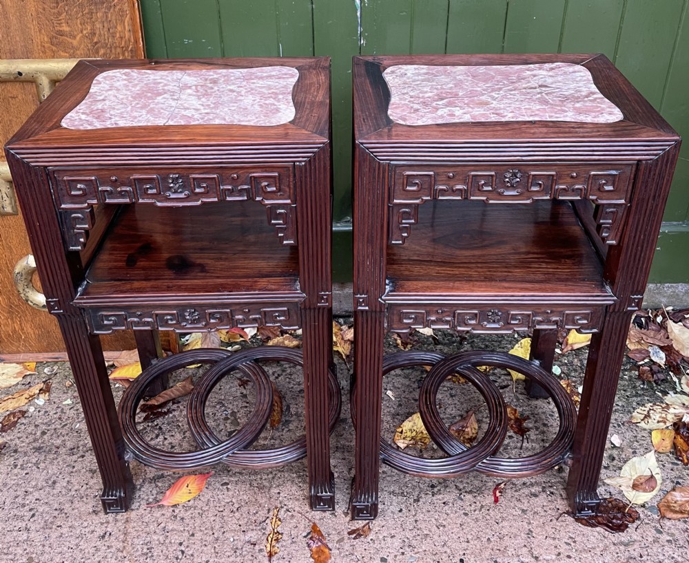 A pair of late nineteenth-century Chinese carved dark hardwood two-tier stands featuring inset marble tops, carved openwork aprons, and interlocking ring stretchers. View XXXI