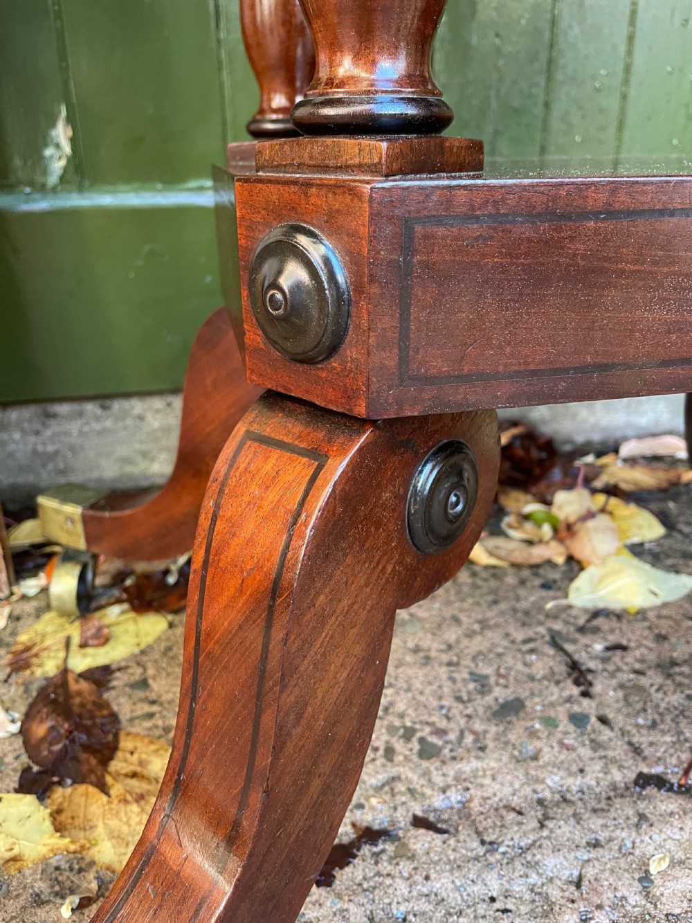 An early 19th-century Regency mahogany fold-over card table featuring turned column supports, a square platform base, and four splayed sabre legs with brass castors. View III