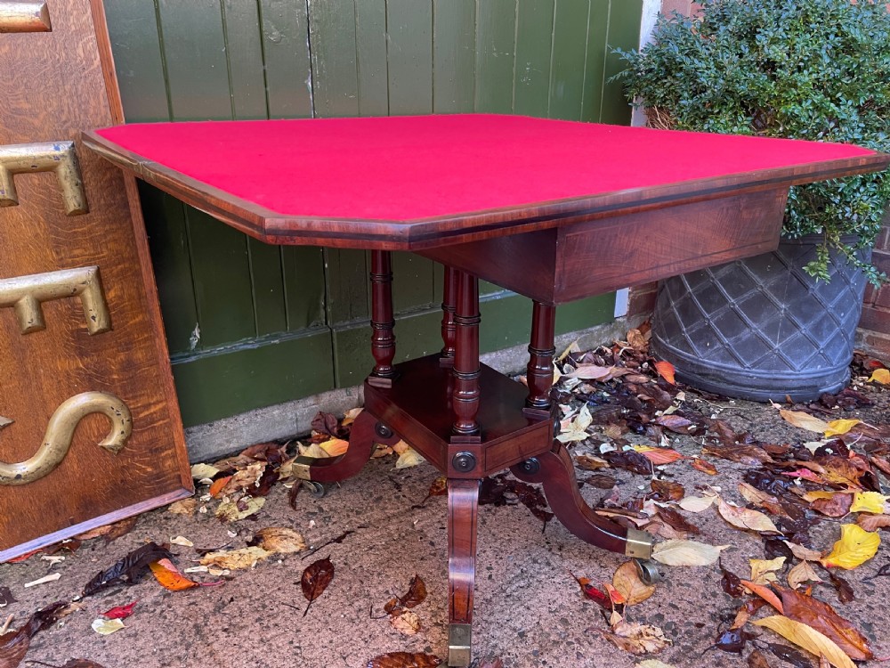 An early 19th-century Regency mahogany fold-over card table featuring turned column supports, a square platform base, and four splayed sabre legs with brass castors. View VIII