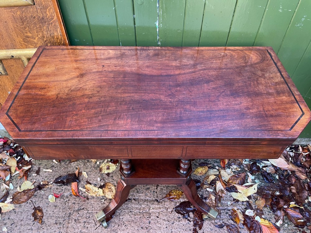 An early 19th-century Regency mahogany fold-over card table featuring turned column supports, a square platform base, and four splayed sabre legs with brass castors. View XIV