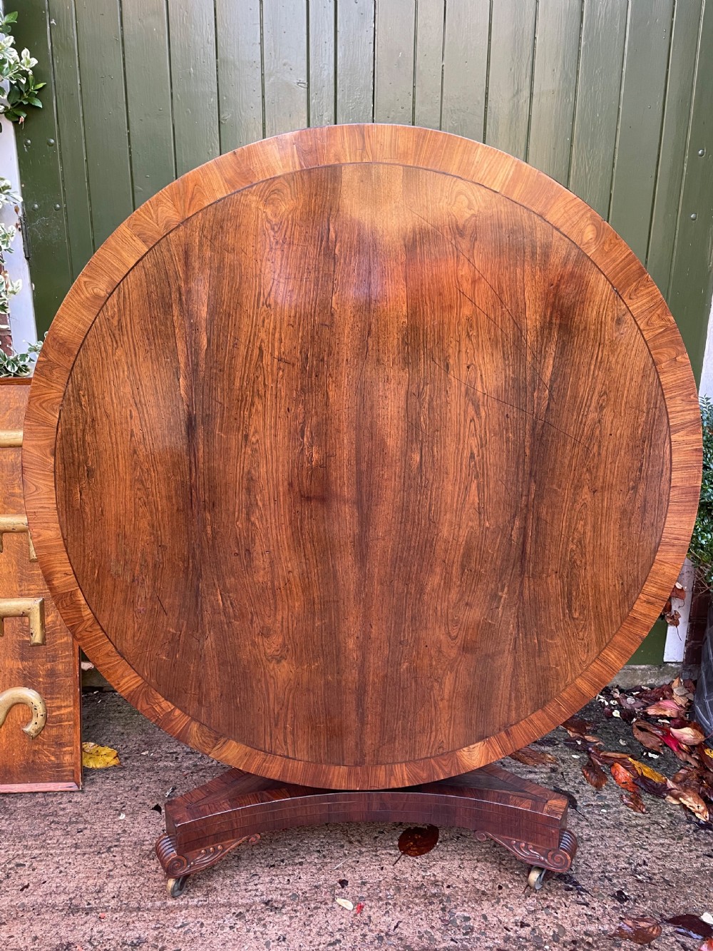 An early nineteenth-century circular Regency rosewood centre table featuring a crossbanded border, displayed in a tilted position on a pedestal base with castors.