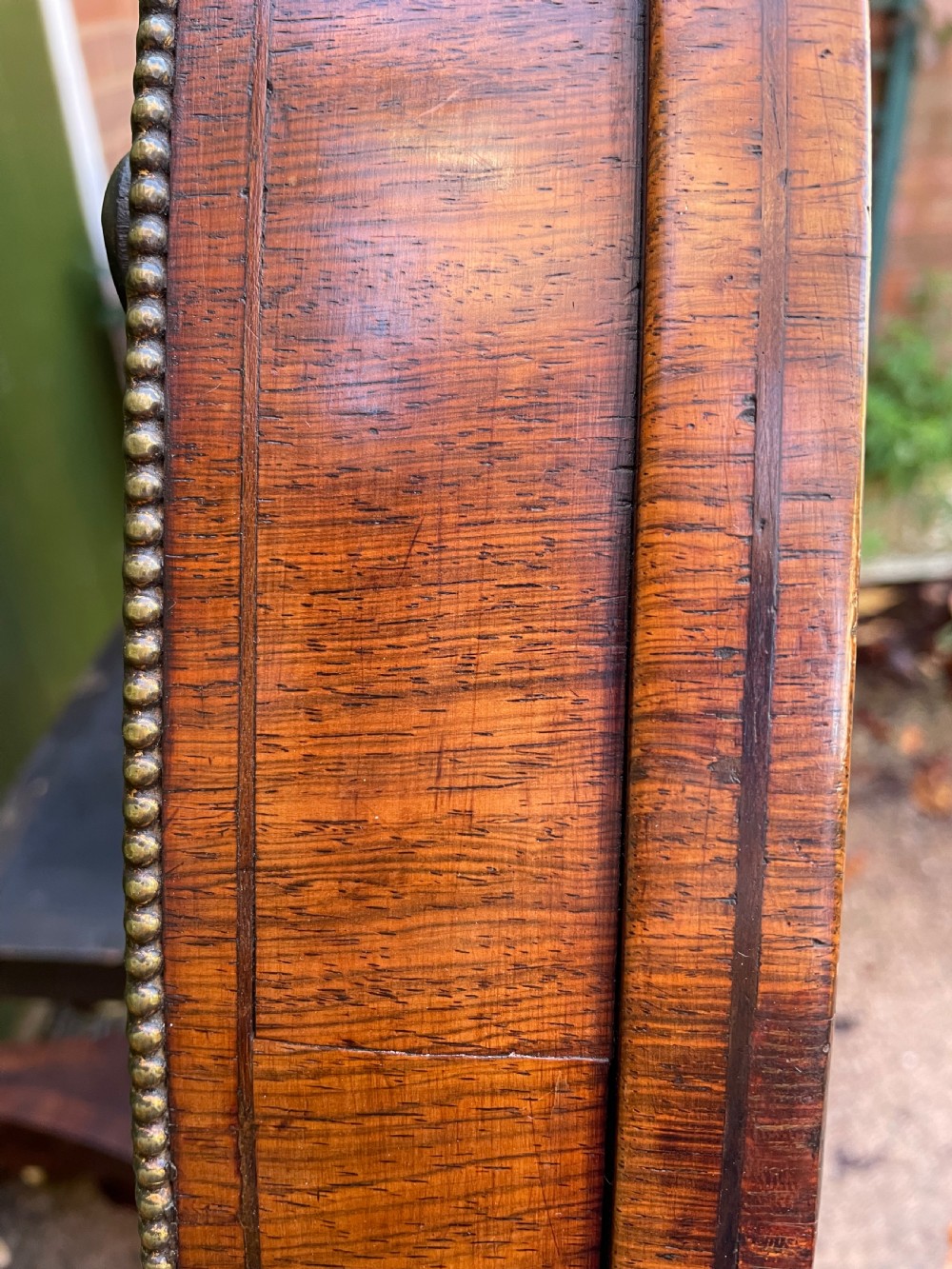 An early nineteenth-century circular Regency rosewood centre table featuring a crossbanded border, displayed in a tilted position on a pedestal base with castors. View III