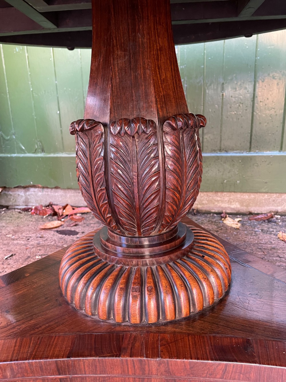An early nineteenth-century circular Regency rosewood centre table featuring a crossbanded border, displayed in a tilted position on a pedestal base with castors. View VIII
