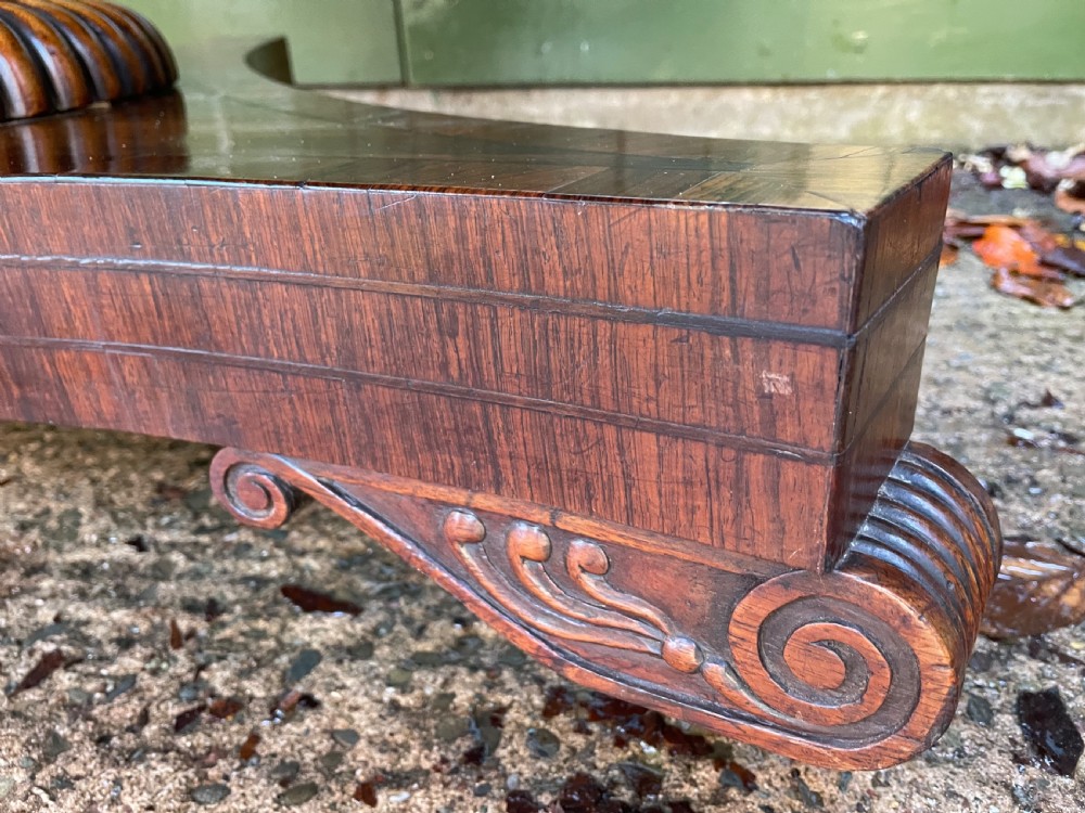 An early nineteenth-century circular Regency rosewood centre table featuring a crossbanded border, displayed in a tilted position on a pedestal base with castors. View IX