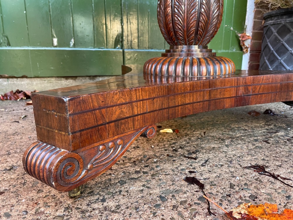 An early nineteenth-century circular Regency rosewood centre table featuring a crossbanded border, displayed in a tilted position on a pedestal base with castors. View XII