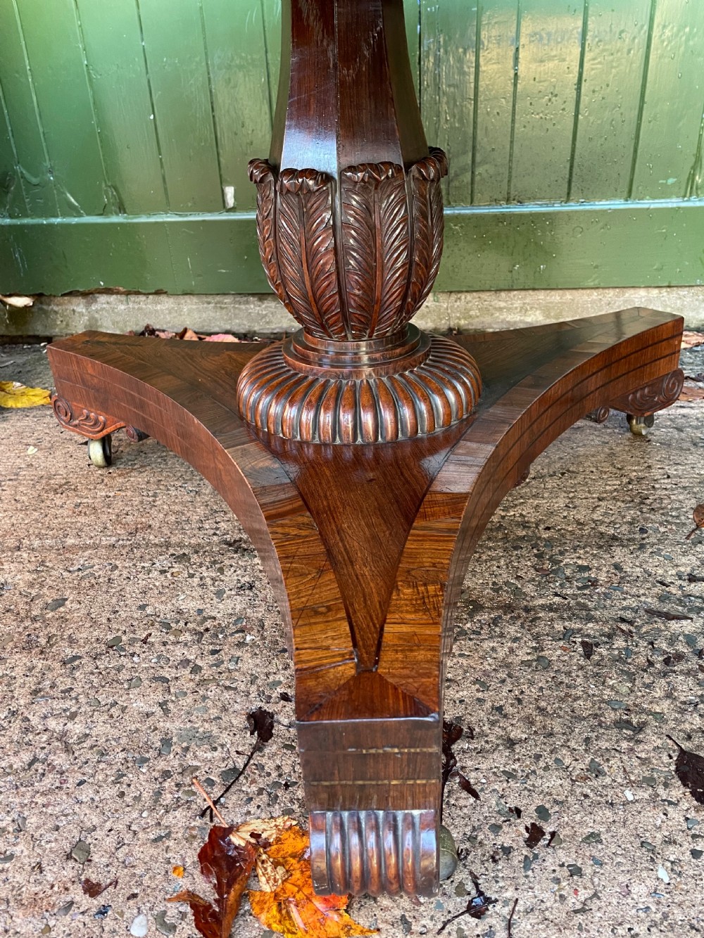 An early nineteenth-century circular Regency rosewood centre table featuring a crossbanded border, displayed in a tilted position on a pedestal base with castors. View XIII