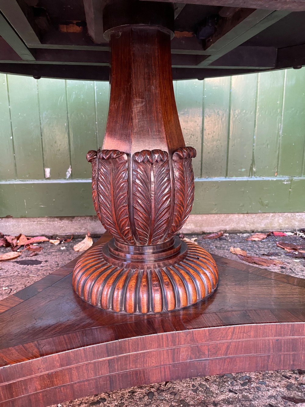 An early nineteenth-century circular Regency rosewood centre table featuring a crossbanded border, displayed in a tilted position on a pedestal base with castors. View XV