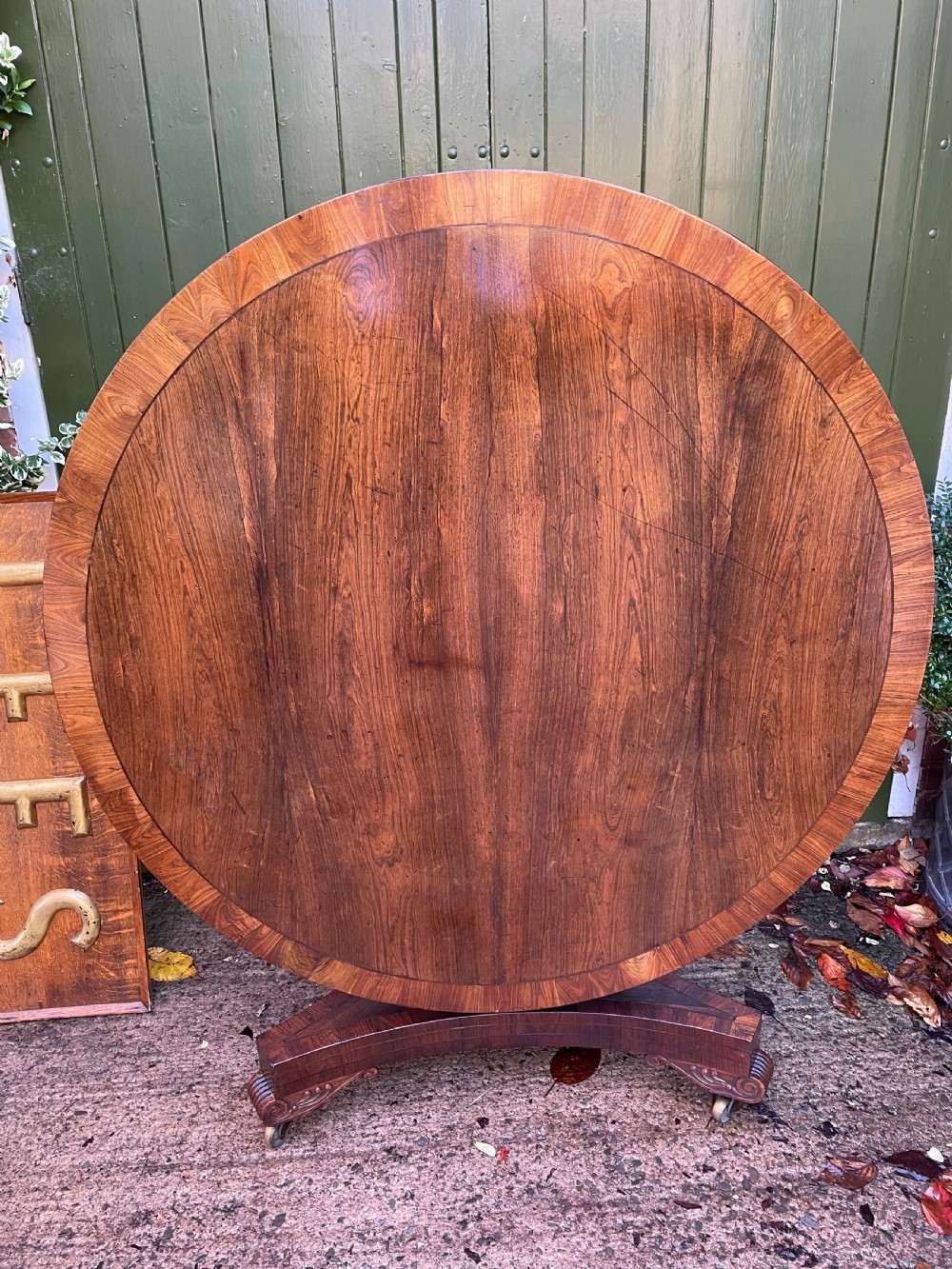 An early nineteenth-century circular Regency rosewood centre table featuring a crossbanded border, displayed in a tilted position on a pedestal base with castors. View XVII