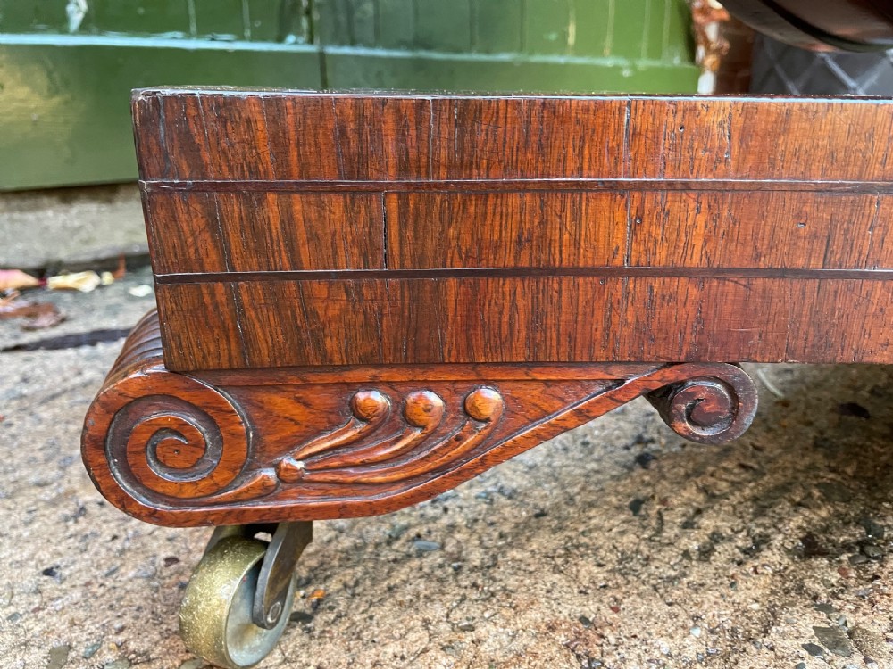 An early nineteenth-century circular Regency rosewood centre table featuring a crossbanded border, displayed in a tilted position on a pedestal base with castors. View XXI