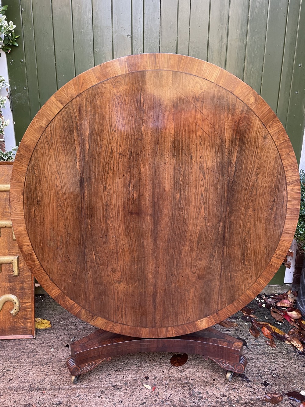 An early nineteenth-century circular Regency rosewood centre table featuring a crossbanded border, displayed in a tilted position on a pedestal base with castors. View XXIV