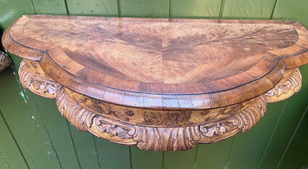 A pair of late nineteenth century carved walnut and parcel-gilt wall consoles with matching arch-top mirrors featuring urn and floral cresting. View IX