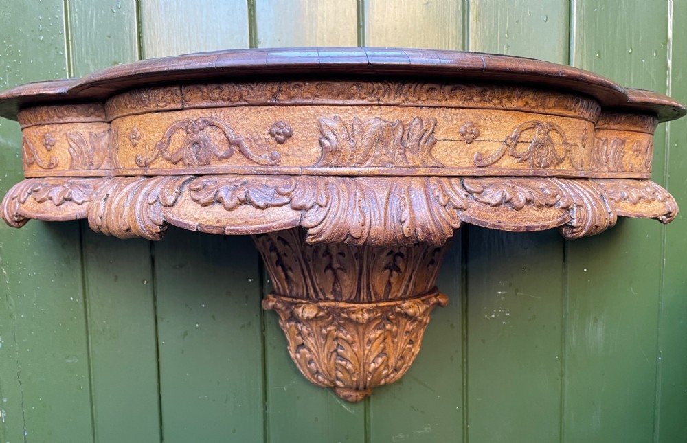 A pair of late nineteenth century carved walnut and parcel-gilt wall consoles with matching arch-top mirrors featuring urn and floral cresting. View X