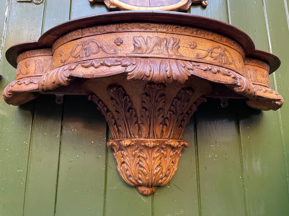 A pair of late nineteenth century carved walnut and parcel-gilt wall consoles with matching arch-top mirrors featuring urn and floral cresting. View XI
