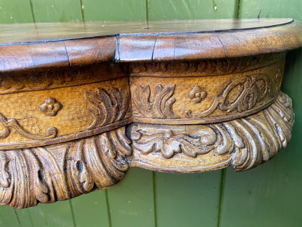 A pair of late nineteenth century carved walnut and parcel-gilt wall consoles with matching arch-top mirrors featuring urn and floral cresting. View XXIV