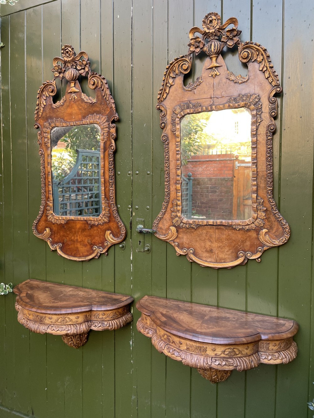A pair of late nineteenth century carved walnut and parcel-gilt wall consoles with matching arch-top mirrors featuring urn and floral cresting. View II