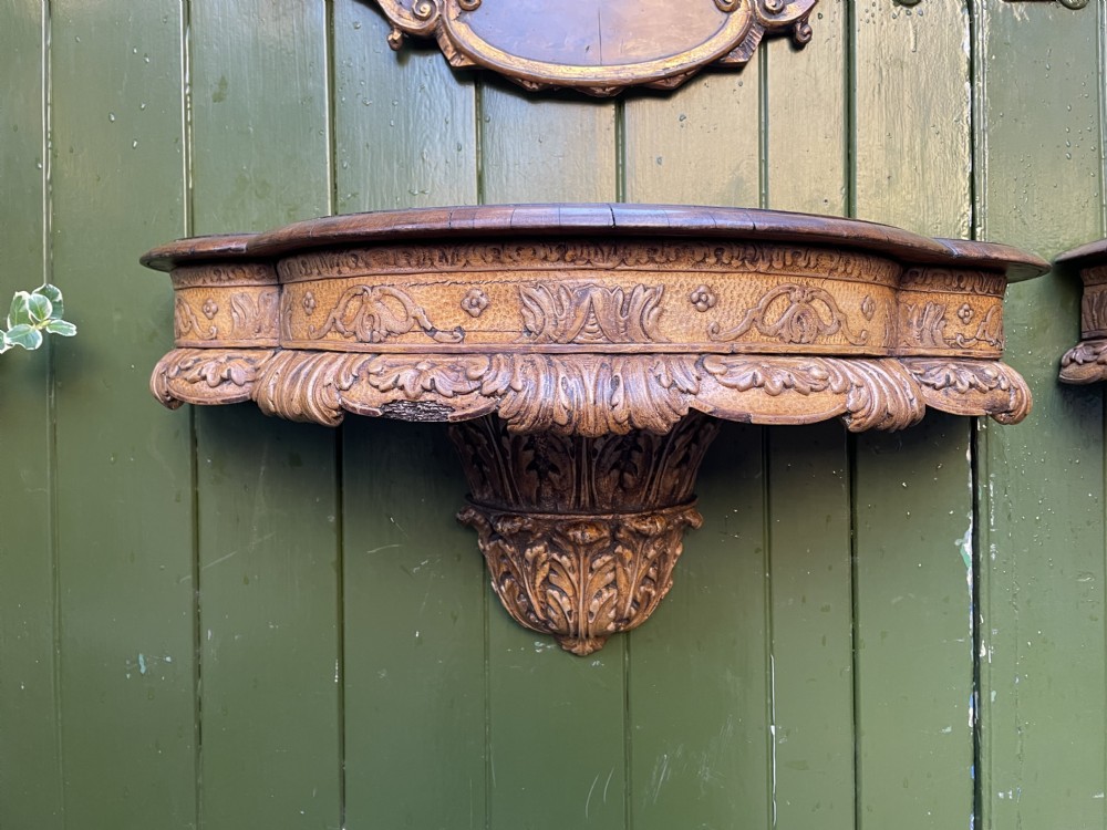 A pair of late nineteenth century carved walnut and parcel-gilt wall consoles with matching arch-top mirrors featuring urn and floral cresting. View XXIX