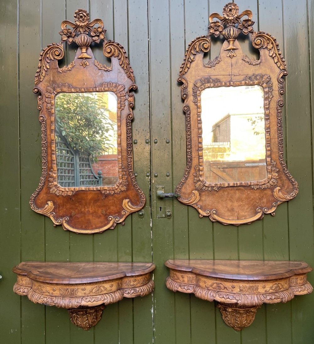 A pair of late nineteenth century carved walnut and parcel-gilt wall consoles with matching arch-top mirrors featuring urn and floral cresting. View XXX