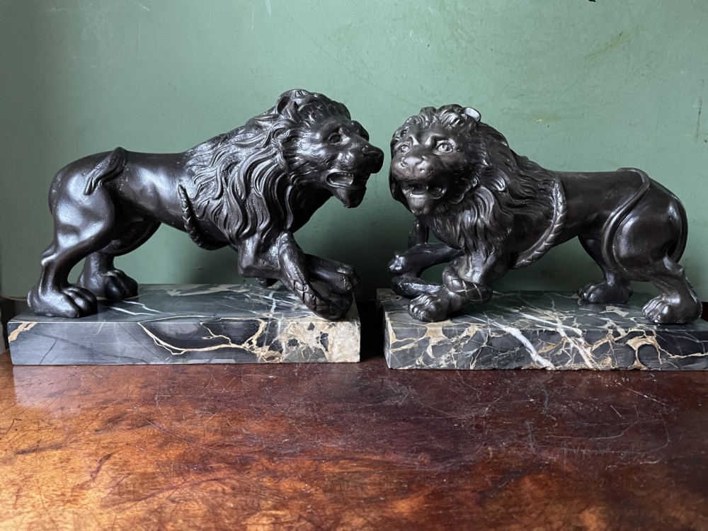 Pair of C19th French cast-iron lions with a bronze patination, mounted on portoro marble plinth bases .