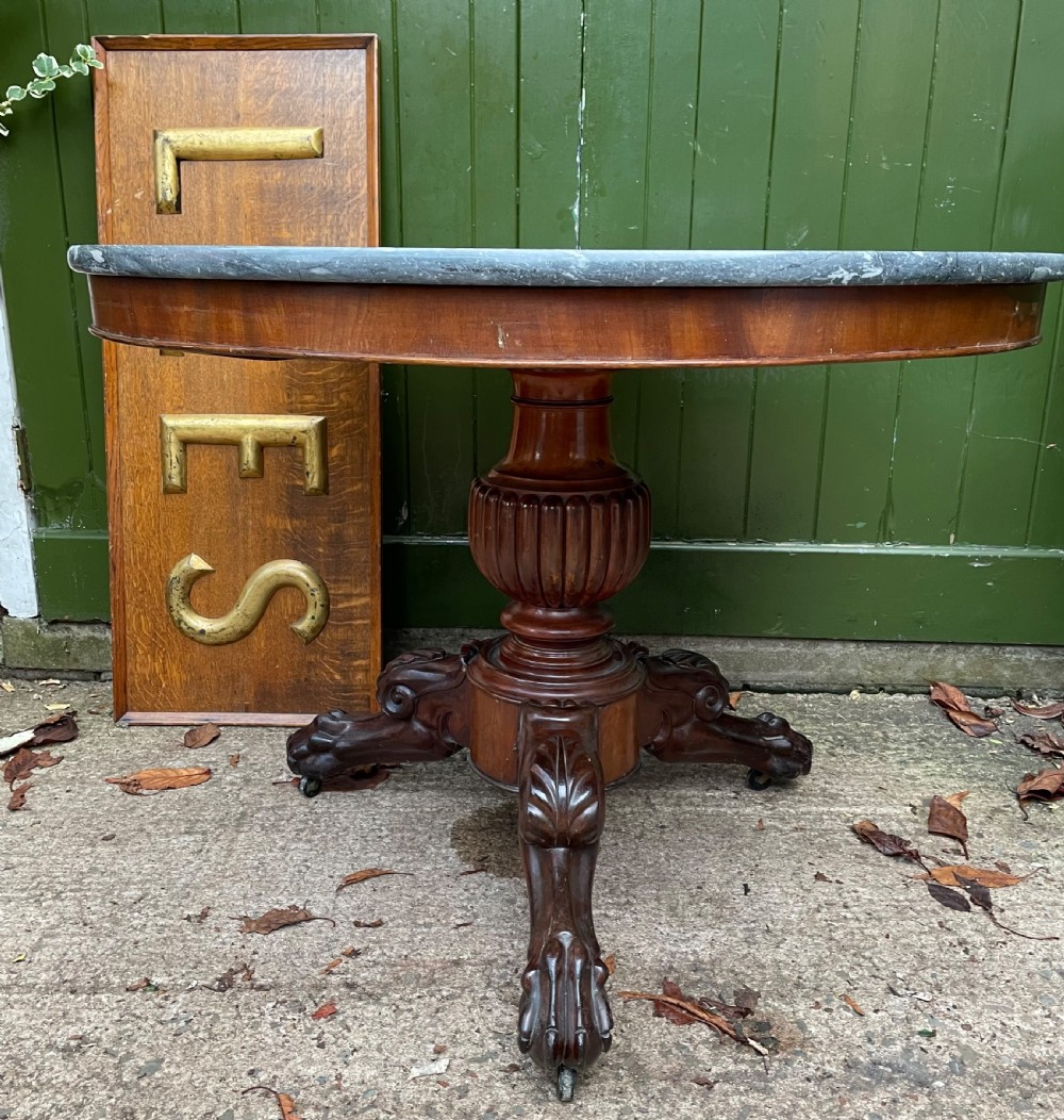 An early nineteenth-century French Charles X mahogany gueridon table featuring a circular grey marble top set upon a fluted pedestal stem and scrolled tripod feet. View X