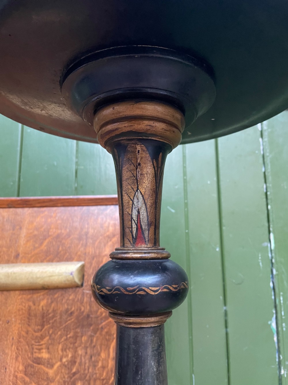 A black lacquered wooden torchere stand featuring gilt floral chinoiserie decoration, a turned central shaft, and a tripod base. View VII
