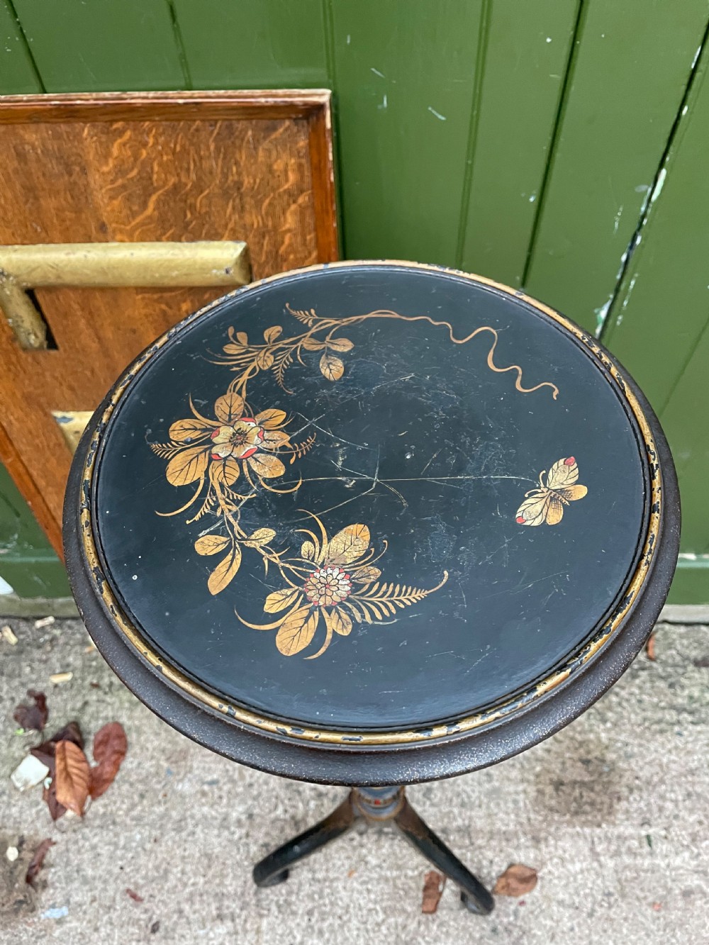 A black lacquered wooden torchere stand featuring gilt floral chinoiserie decoration, a turned central shaft, and a tripod base. View VIII