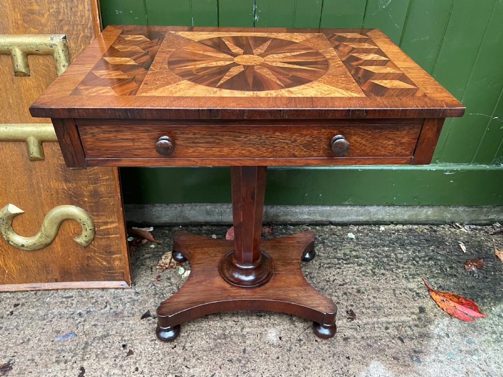 A nineteenth-century rectangular rosewood side table featuring a starburst specimen wood inlaid top set on a pedestal base with a quadform platform. View II