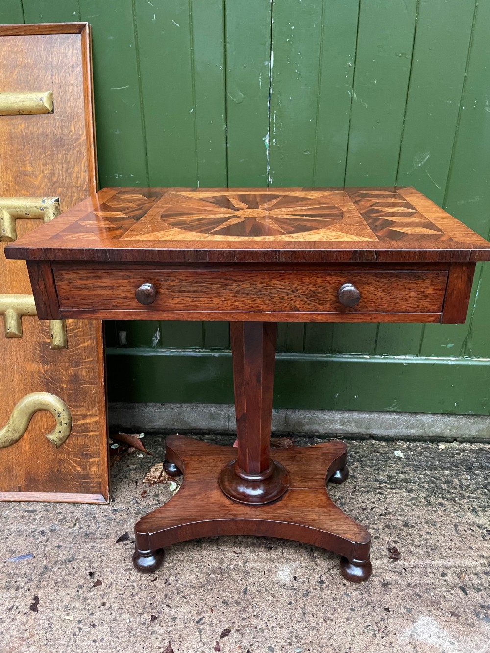 A nineteenth-century rectangular rosewood side table featuring a starburst specimen wood inlaid top set on a pedestal base with a quadform platform. View V