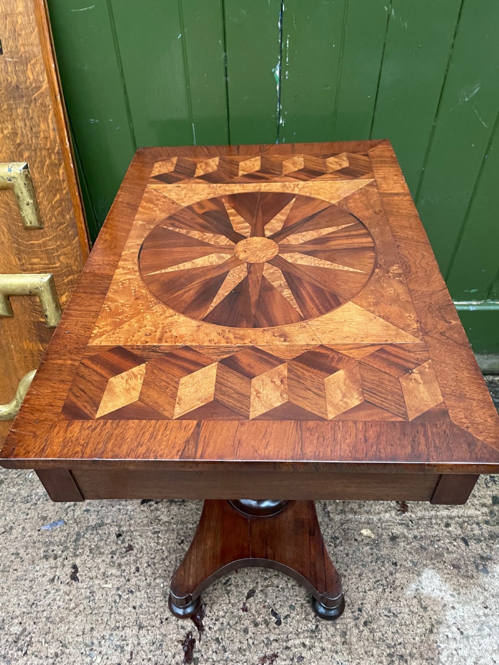A nineteenth-century rectangular rosewood side table featuring a starburst specimen wood inlaid top set on a pedestal base with a quadform platform. View VII