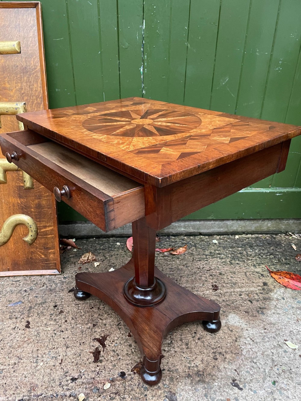 A nineteenth-century rectangular rosewood side table featuring a starburst specimen wood inlaid top set on a pedestal base with a quadform platform. View IX